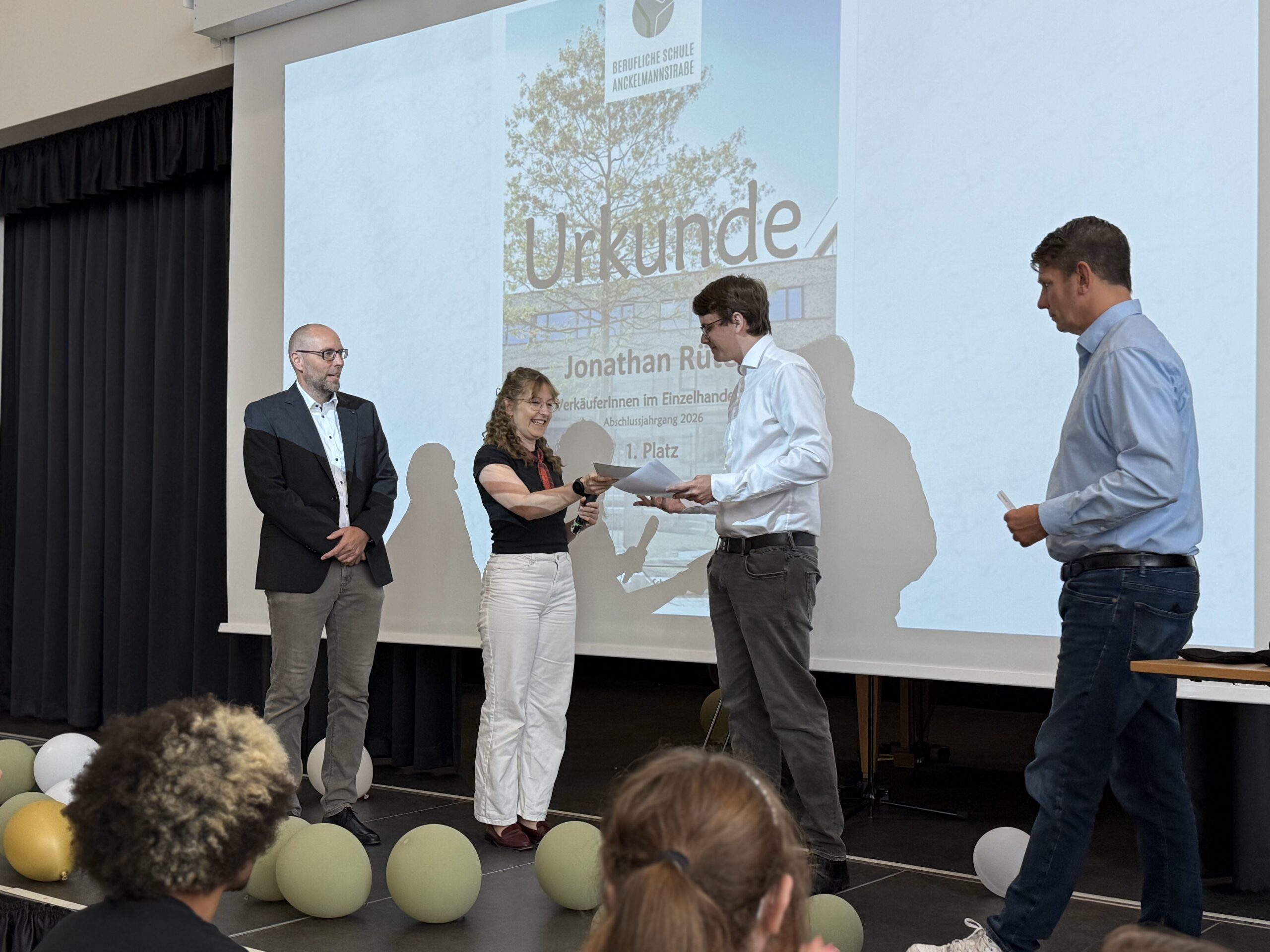 Lehrerin übergibt Urkunde an Schüler