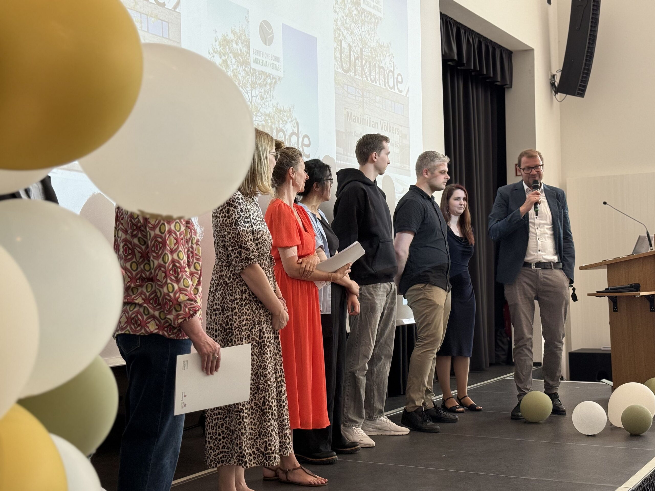 Gruppe von Schülern und Lehrer mit Abteilungsleiter auf der Bühne